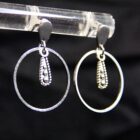 Darkness drop minimalist punk earrings in silver. with a teardrop shaped stainless steel clasp, hoops and a detailed teardrop charm.