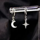 Mismatched witchy earrings featuring a star and a moon, with stainless steel clasps